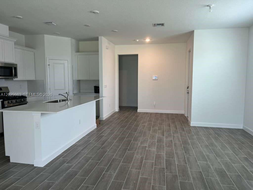 A kitchen with white cabinets and a breakfast bar opens to a tiled living area — 19788 Whispering Creek Rd # 19788, Loxahatchee FL 33470, LOXAHATCHEE, FL