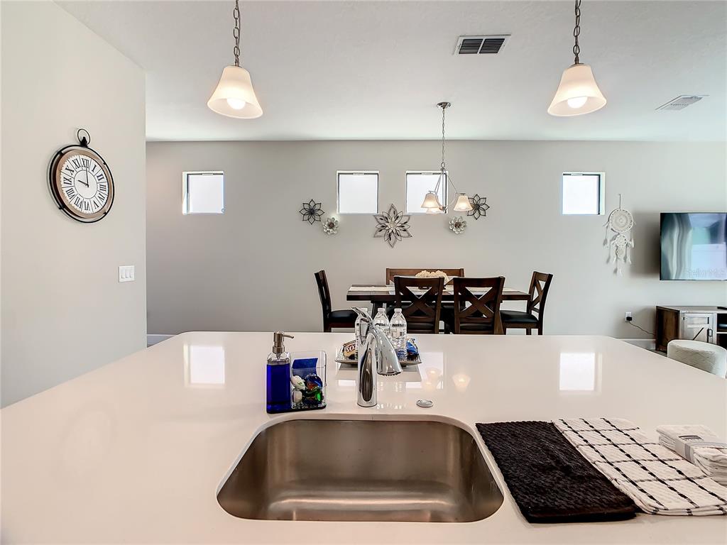 A kitchen island with a stainless steel sink overlooks a dining area with four chairs — 208 VILLA DOMANI CIRCLE, DAVENPORT, FL