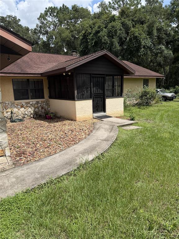 A tan house with a stone facade, a brown roof, and a screened-in front porch — 14787 SE 36TH AVENUE, SUMMERFIELD, FL