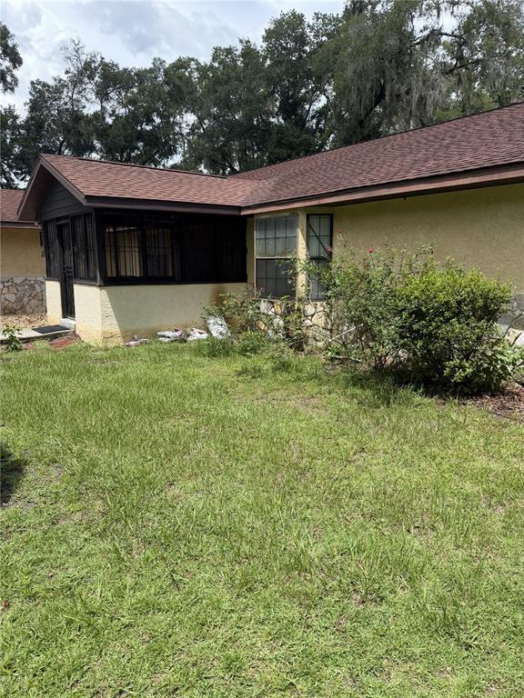 A yellow stucco house features a screened-in porch and a brown shingled roof — 14787 SE 36TH AVENUE, SUMMERFIELD, FL