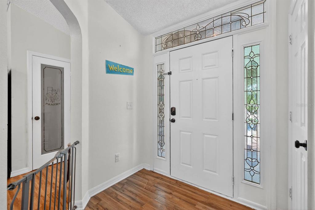 An entryway features a white front door with sidelights, a pantry door, and wood flooring — 16 REGENCY DRIVE, PALM COAST, FL