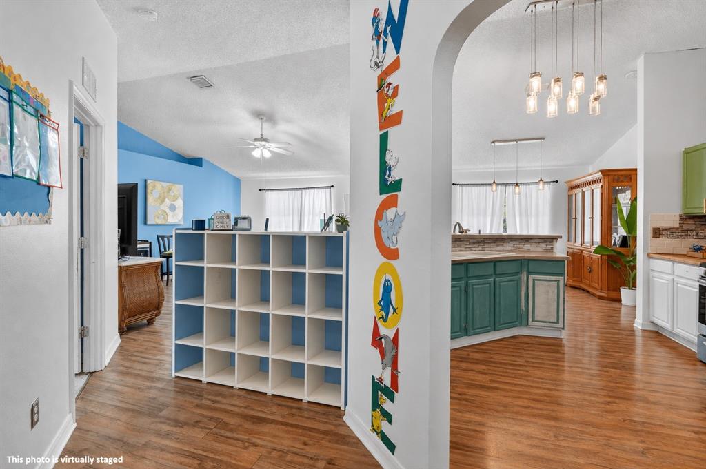 A view through an arched doorway showing a living area and a kitchen with wood floors — 16 REGENCY DRIVE, PALM COAST, FL