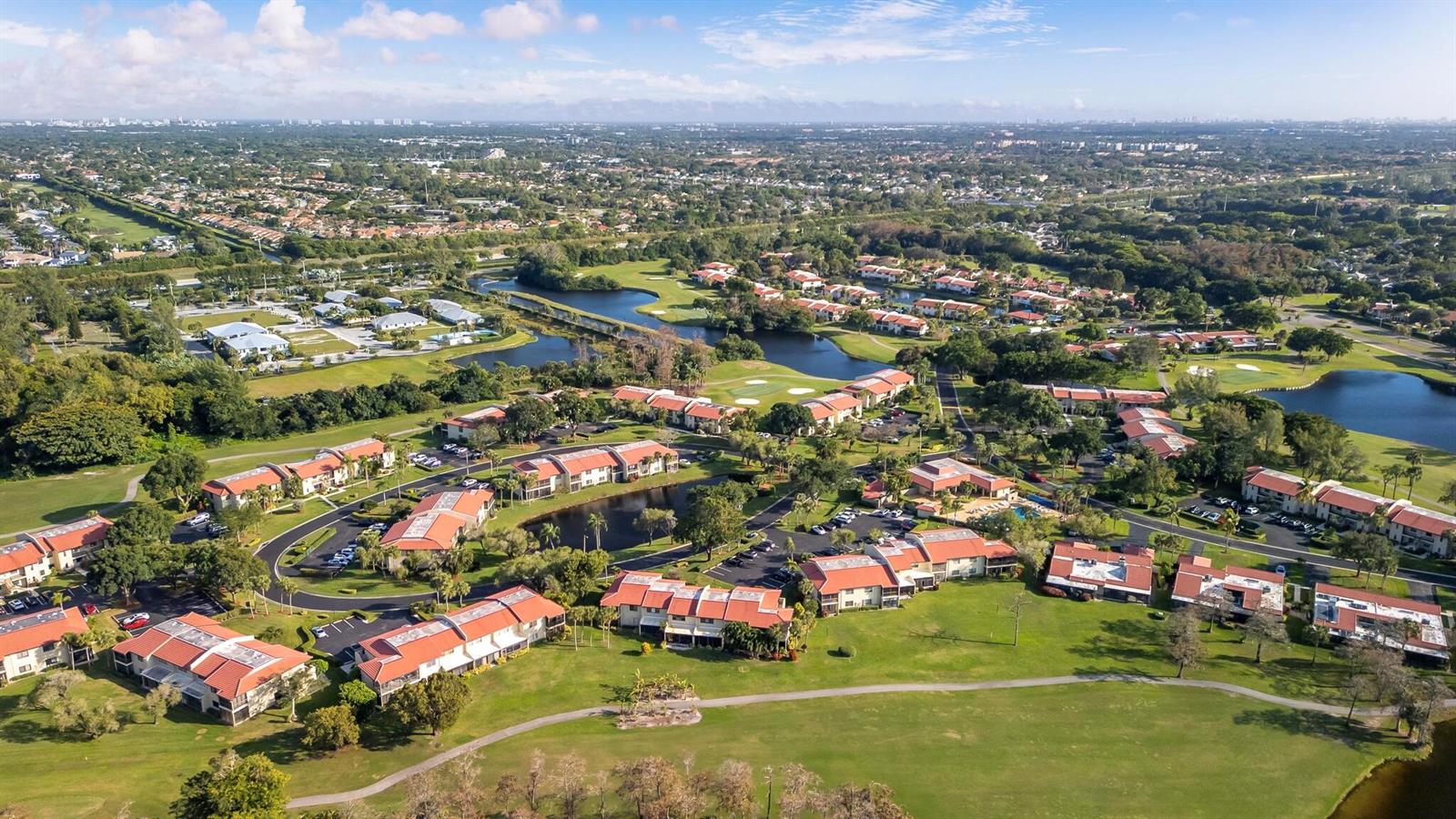 An aerial view shows a residential community with red-roofed buildings surrounded by golf course greens — 21218 Lago Circle # F, Boca Raton FL 33433, BOCA RATON, FL