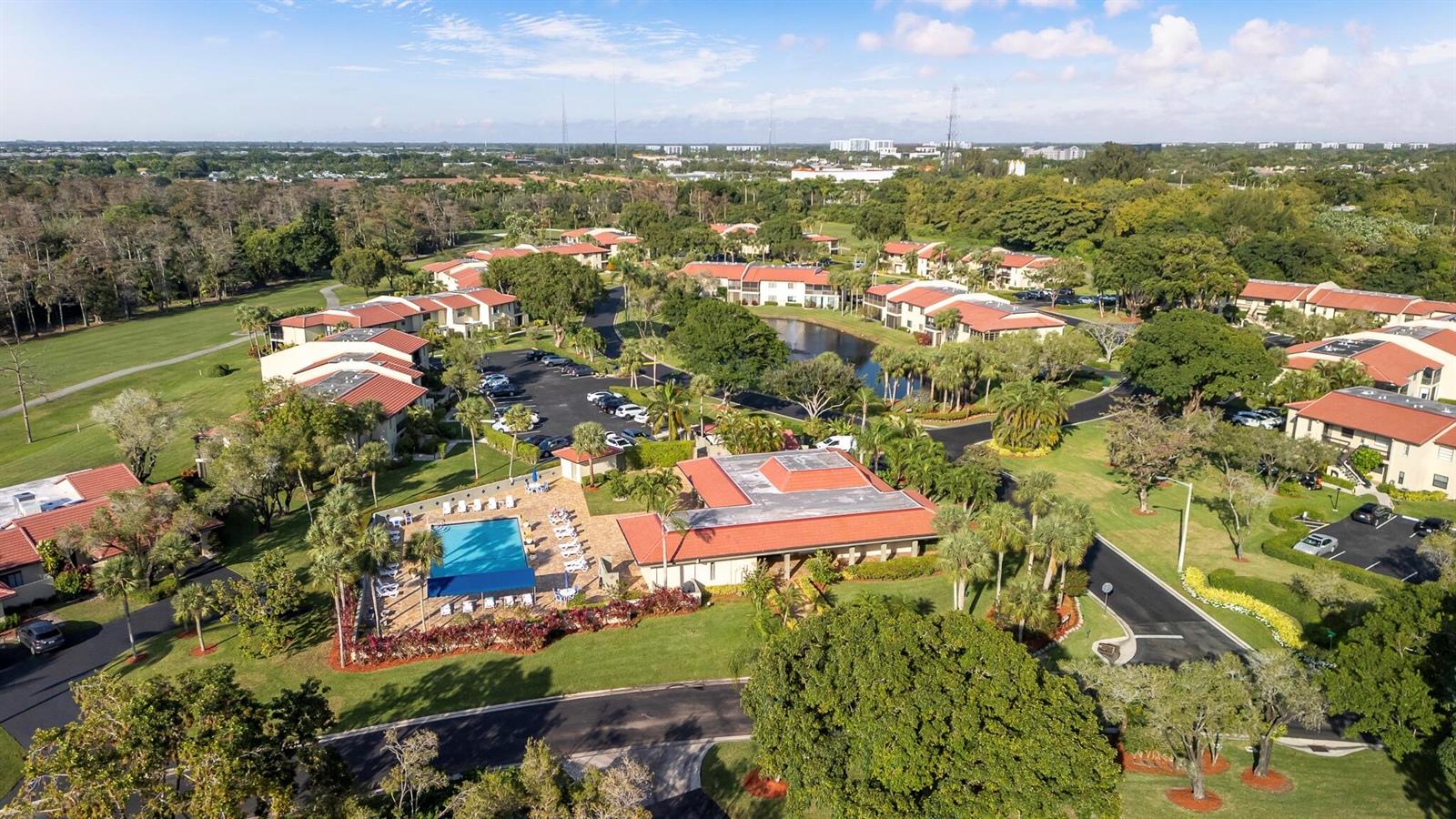 An aerial view shows a residential complex with a swimming pool, clubhouse, and surrounding greenery — 21218 Lago Circle # F, Boca Raton FL 33433, BOCA RATON, FL