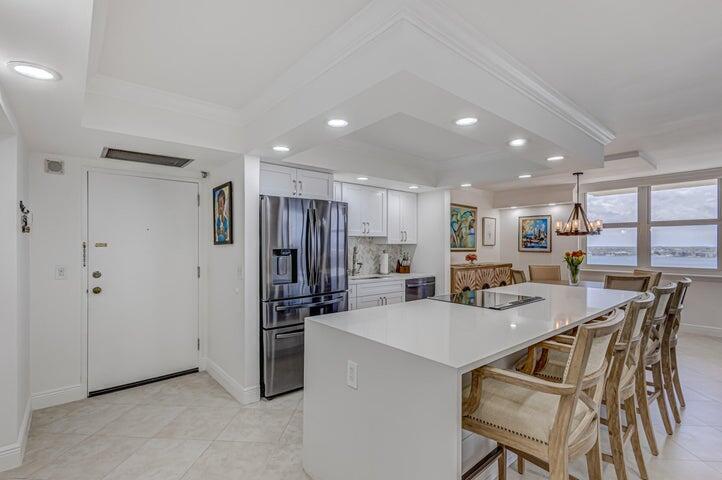 A modern kitchen features a large white island, stainless steel appliances, and light tile flooring — 5440 N Ocean Drive # 1502, Singer Island FL 33404, SINGER ISLAND, FL
