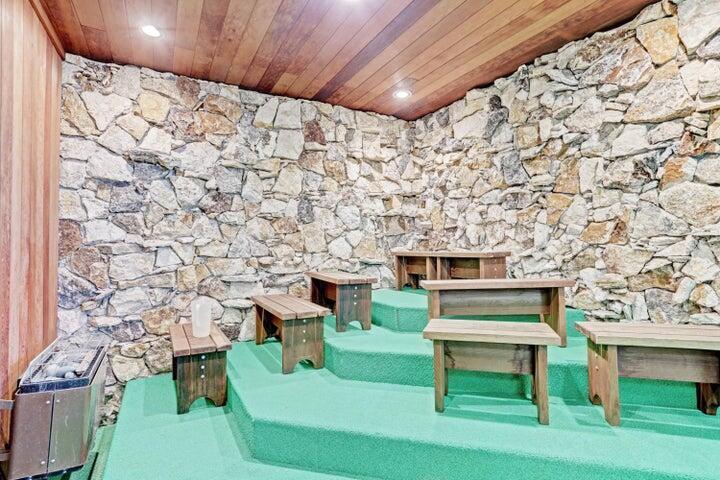 A sauna room features tiered green platforms, wooden benches, and a natural stone wall — 5440 N Ocean Drive # 1502, Singer Island FL 33404, SINGER ISLAND, FL