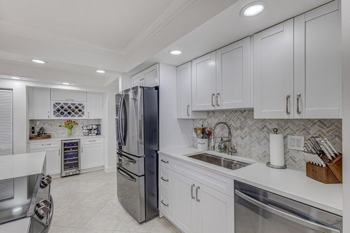 A modern kitchen features white cabinetry, stainless steel appliances, and a herringbone tile backsplash — 5440 N Ocean Drive # 1502, Singer Island FL 33404, SINGER ISLAND, FL