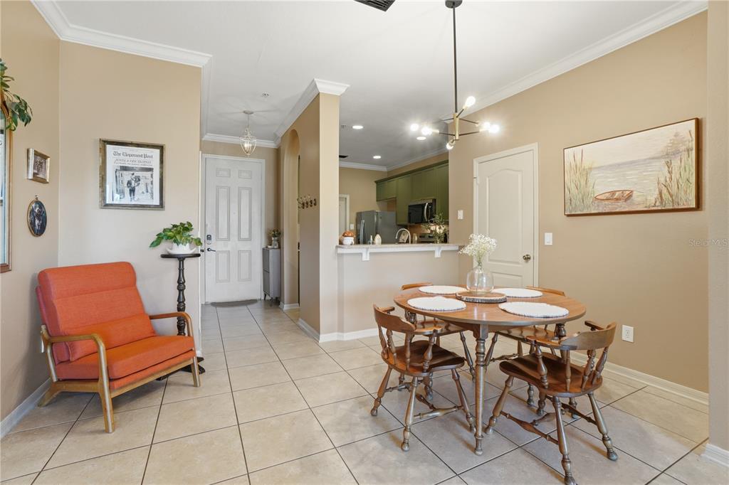 A dining area with a round wooden table, chairs, and an adjacent entryway with tile flooring — 3028 CAPRI ISLE WAY, ORLANDO, FL
