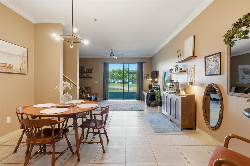 A dining area with wooden furniture leads into a living space with tile flooring — 3028 CAPRI ISLE WAY, ORLANDO, FL