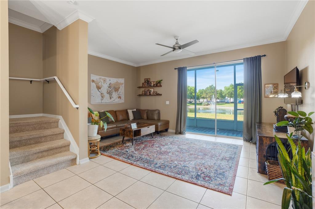 A living room features tile flooring, a sectional sofa, a staircase, and a sliding glass door — 3028 CAPRI ISLE WAY, ORLANDO, FL