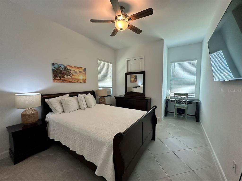 A bedroom features a dark wood bed frame, a dresser with a mirror, and tile flooring — 13372 JOURNAL LANE, PORT CHARLOTTE, FL