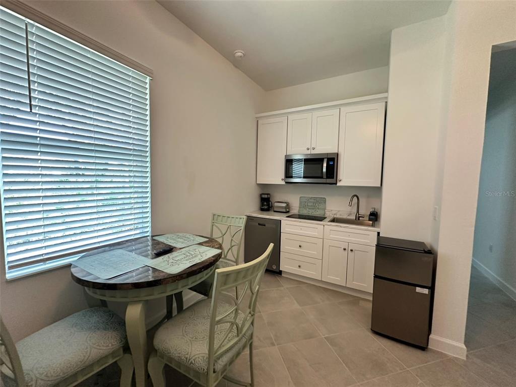 A small kitchen features white cabinets, a microwave, a sink, and a round dining table — 13372 JOURNAL LANE, PORT CHARLOTTE, FL