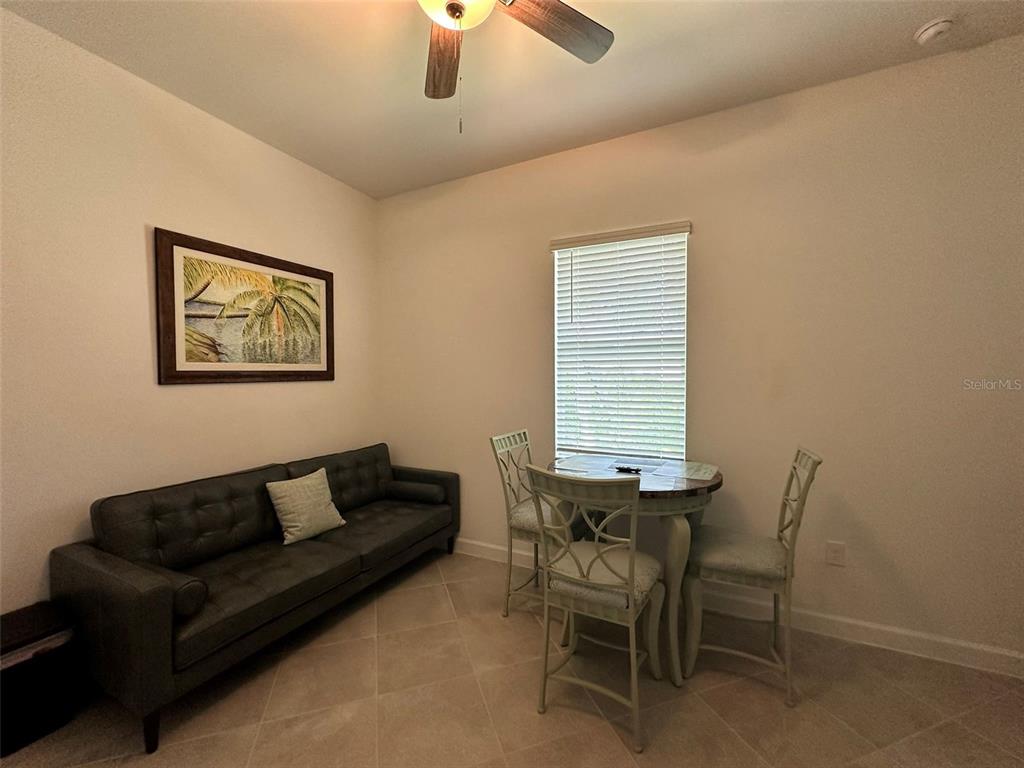 A room features a dark gray sofa, a small dining table with two chairs, and tile flooring — 13372 JOURNAL LANE, PORT CHARLOTTE, FL