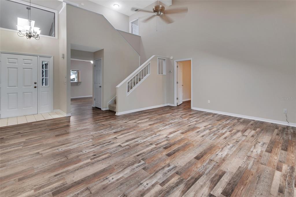 An open living area features wood-look flooring, a high vaulted ceiling, and a staircase — 2919 REVERE PLACE UNIT 2919, DELAND, FL