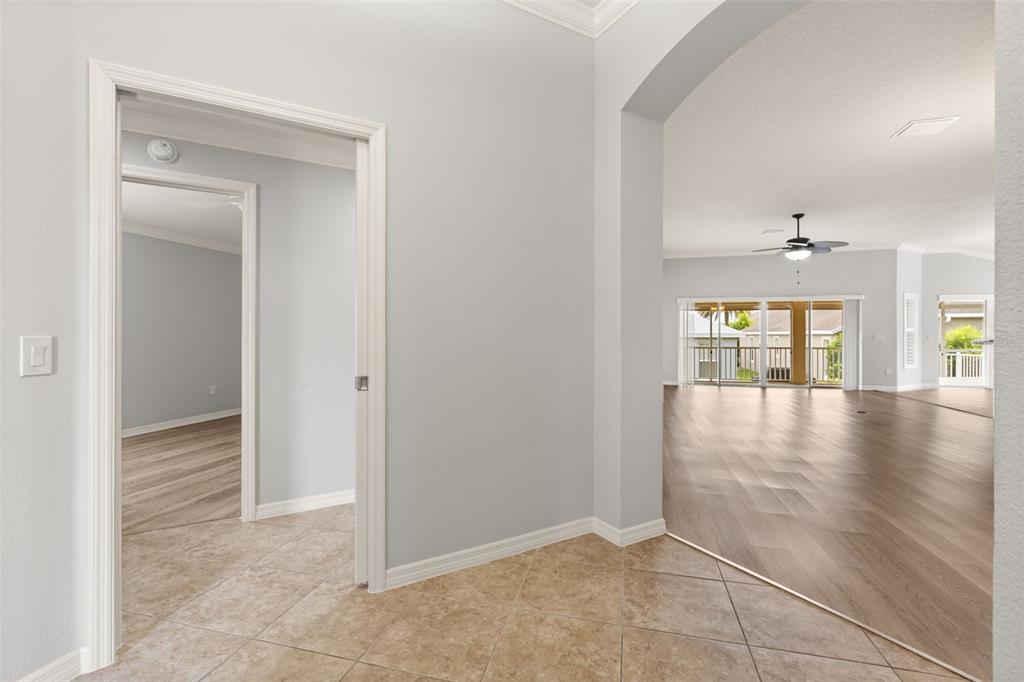 A tiled entryway leads to a light-filled living area with wood-look flooring and sliding doors — 842 PICKETT ROAD, THE VILLAGES, FL