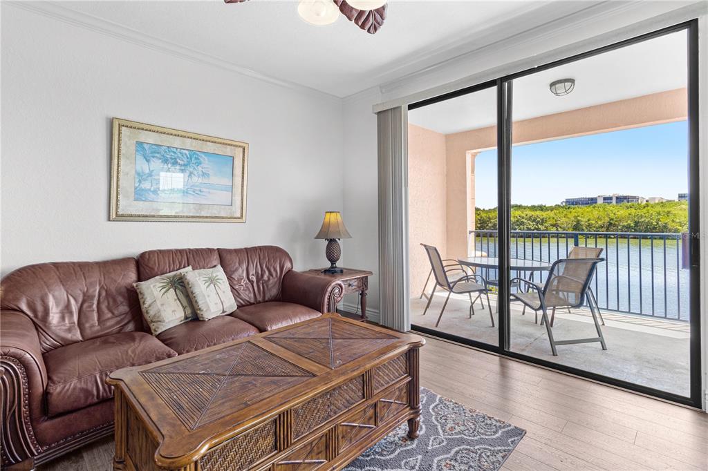 A living room with a leather sofa, wooden coffee table, and sliding doors to a balcony — 2729 VIA MURANO DRIVE UNIT 429, CLEARWATER, FL