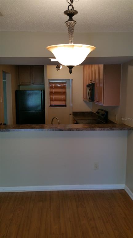 A kitchen with wood-look flooring, a breakfast bar, and a hanging pendant light fixture — 2934 PLAZA TERRACE DRIVE UNIT 2934, ORLANDO, FL