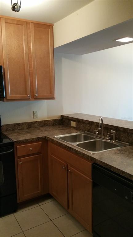 A kitchen features light wood cabinets, dark laminate countertops, and a double-basin stainless steel sink — 2934 PLAZA TERRACE DRIVE UNIT 2934, ORLANDO, FL