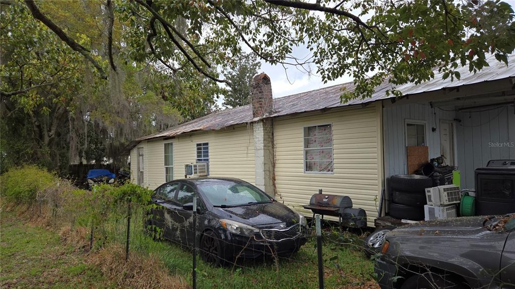 An exterior view of a single-story house with light siding, a metal roof, and chimney — 883 NE MAPLE LANE, LAKE CITY, FL