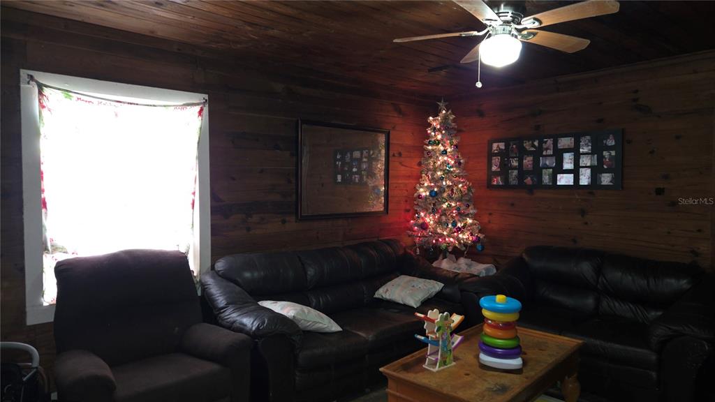 A living room features wood-paneled walls, a leather sofa set, and a decorated Christmas tree — 883 NE MAPLE LANE, LAKE CITY, FL