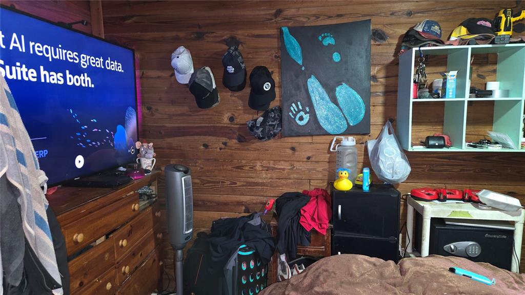A bedroom with wood-paneled walls, a television, a storage unit, and various personal items — 883 NE MAPLE LANE, LAKE CITY, FL