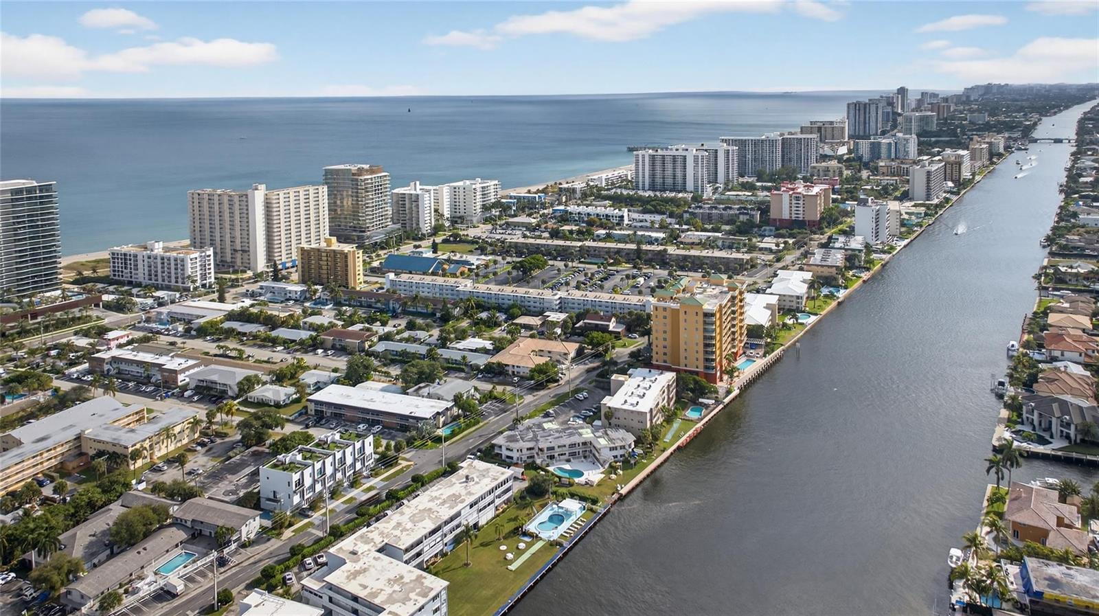 An aerial view shows coastal apartment buildings, a waterway, and the ocean in the distance — 1001 N Riverside Drive # 305, Pompano Beach FL 33062, POMPANO BEACH, FL