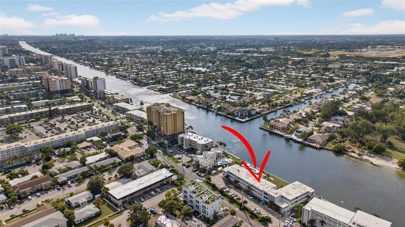 An aerial view shows a multi-story apartment building situated along a canal in Florida — 1001 N Riverside Drive # 305, Pompano Beach FL 33062, POMPANO BEACH, FL