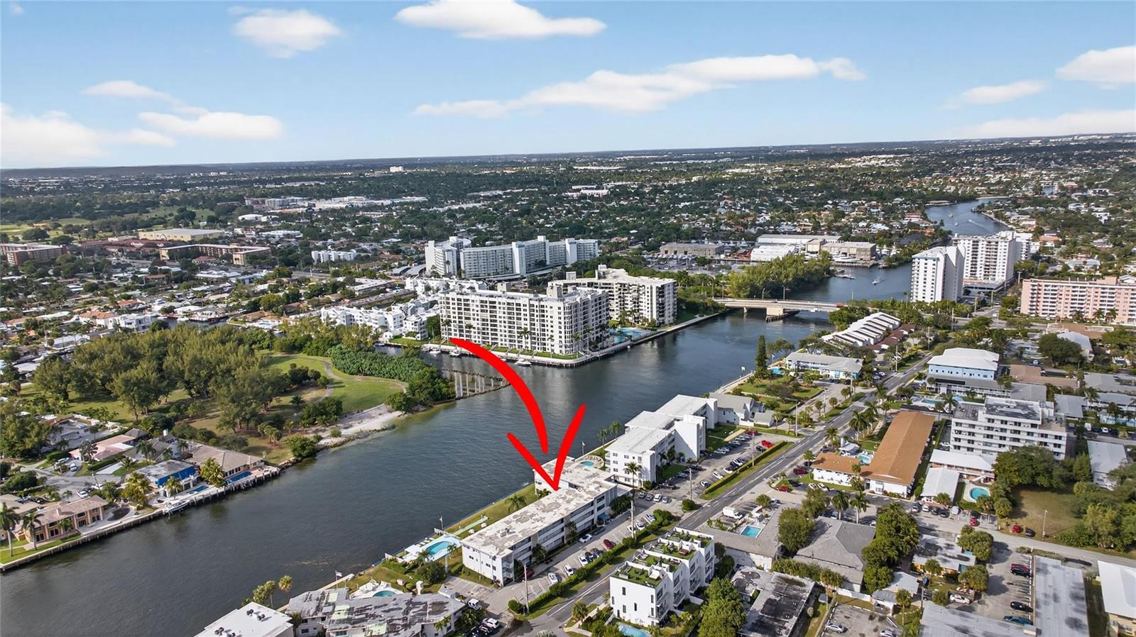 An aerial view shows a multi-story apartment building along a canal in a residential area — 1001 N Riverside Drive # 305, Pompano Beach FL 33062, POMPANO BEACH, FL