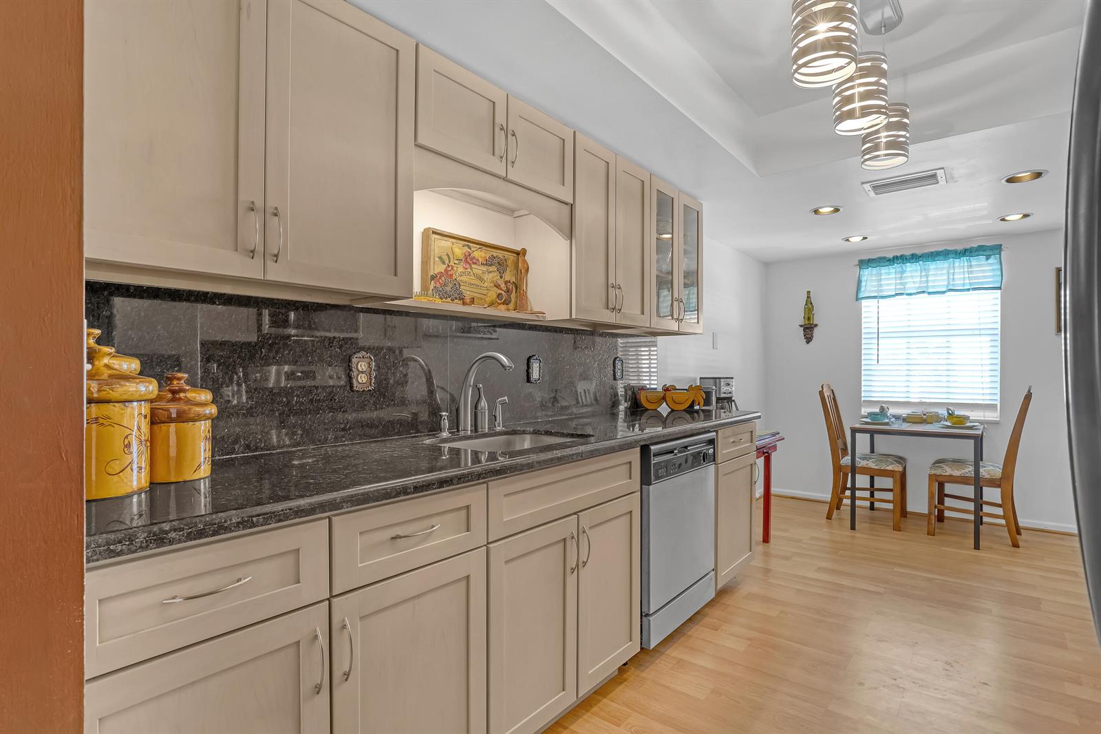 A kitchen with light-colored cabinets, dark granite countertops, and an adjacent dining area — 1250 Sugar Sands Boulevard # 207, Singer Island FL 33404, SINGER ISLAND, FL