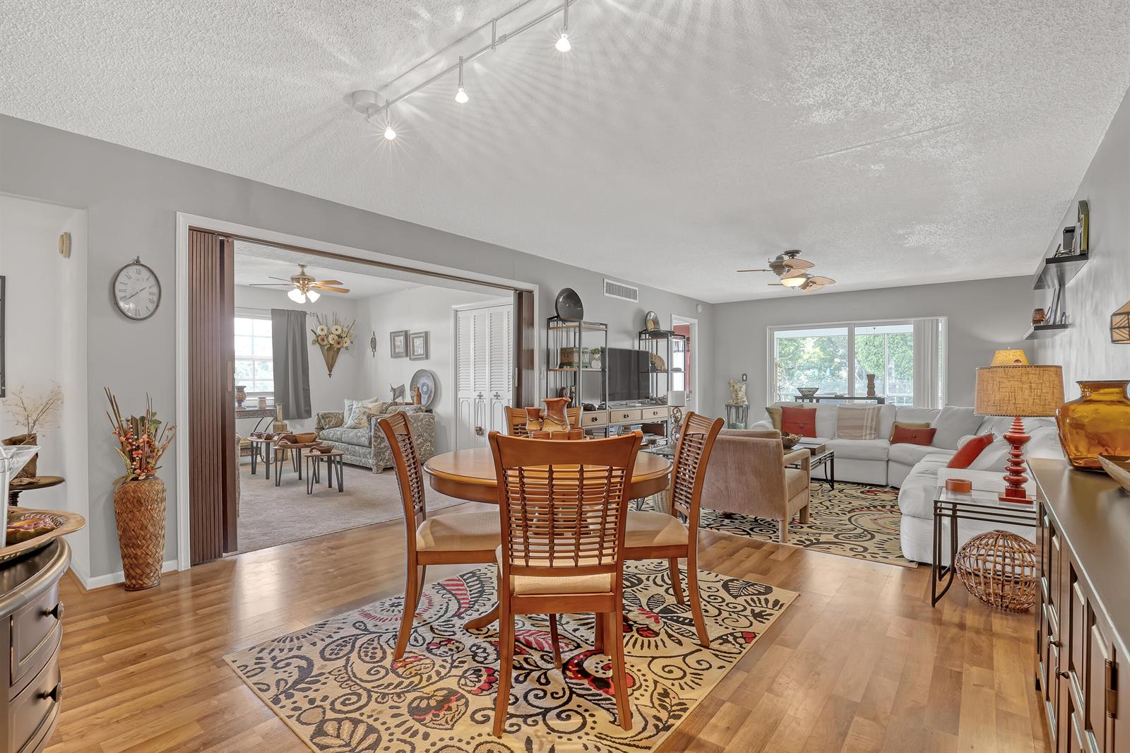 A dining area and living room with wood floors, area rugs, and a track light — 1250 Sugar Sands Boulevard # 207, Singer Island FL 33404, SINGER ISLAND, FL