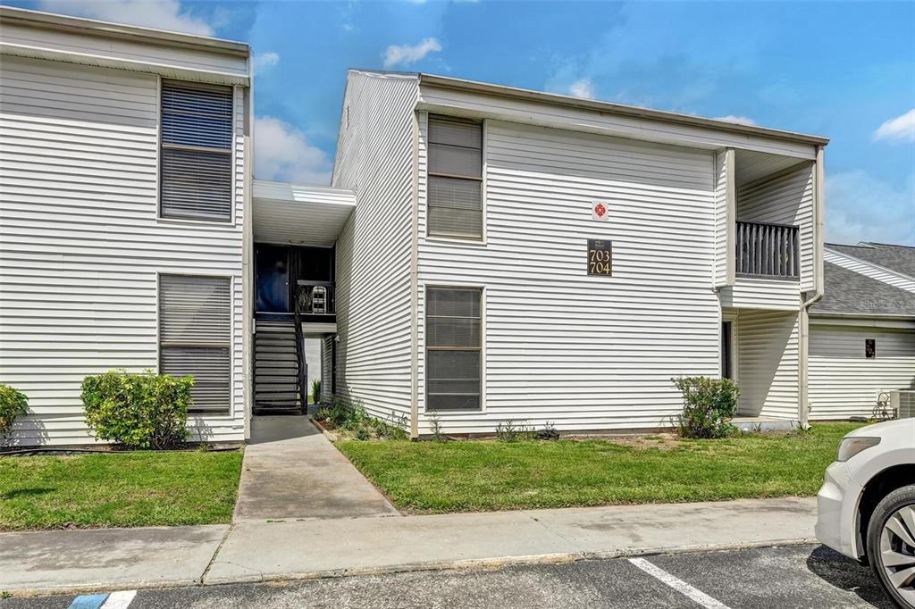 A two-story apartment building with white siding, dark window shutters, and an exterior staircase — 704 HAVEN PLACE UNIT 704, TARPON SPRINGS, FL