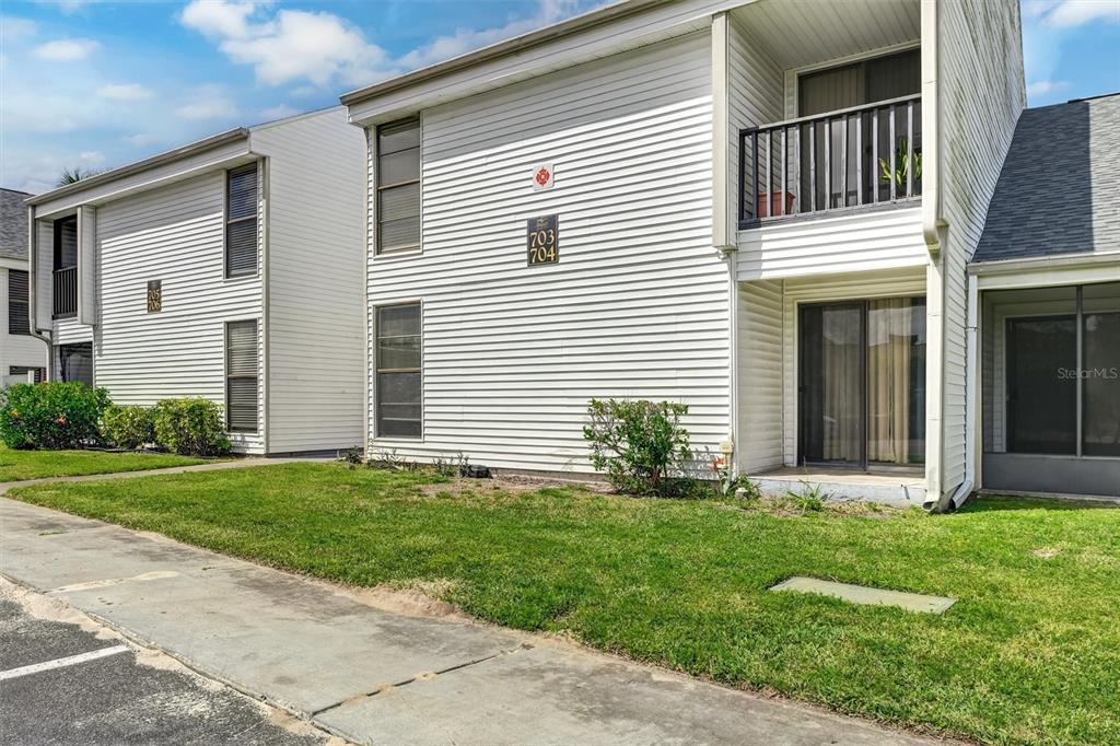 A two-story apartment building with white siding, a balcony, and a screened-in patio — 704 HAVEN PLACE UNIT 704, TARPON SPRINGS, FL