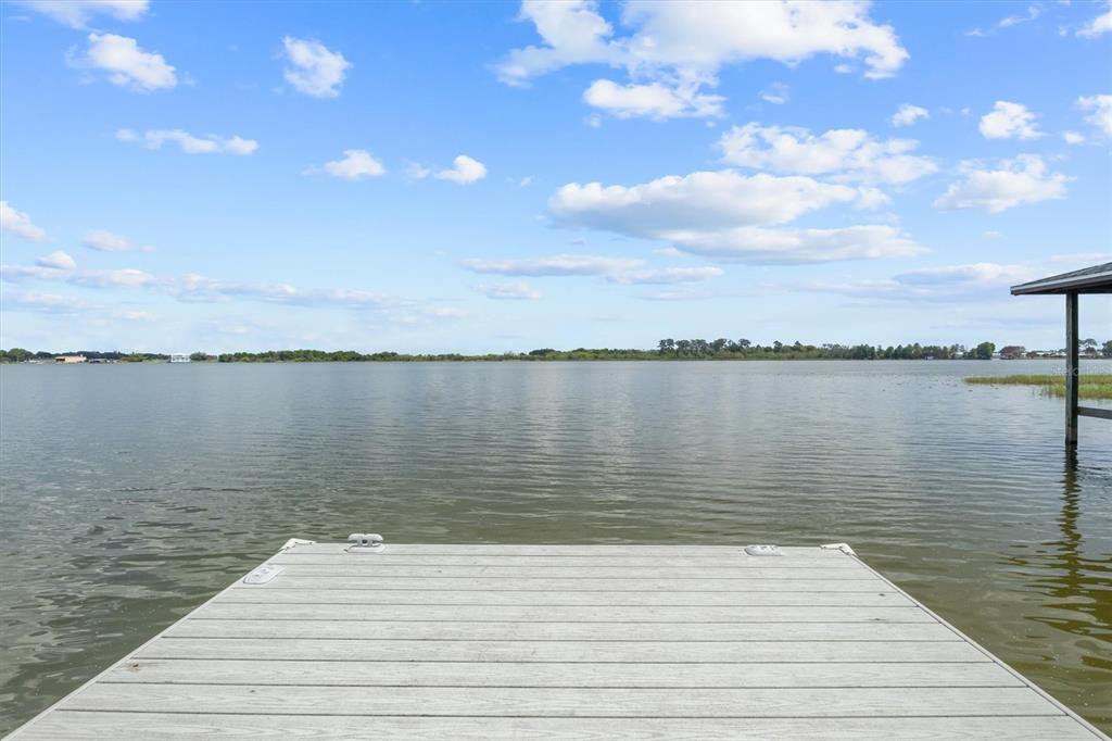 A wooden dock extends into a calm lake under a blue sky with clouds — 900 LAKE JESSIE DRIVE, WINTER HAVEN, FL