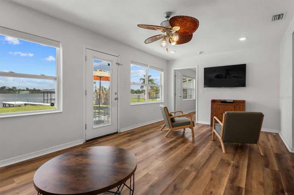 A living room with wood-look flooring, a ceiling fan, and a view of the water — 900 LAKE JESSIE DRIVE, WINTER HAVEN, FL