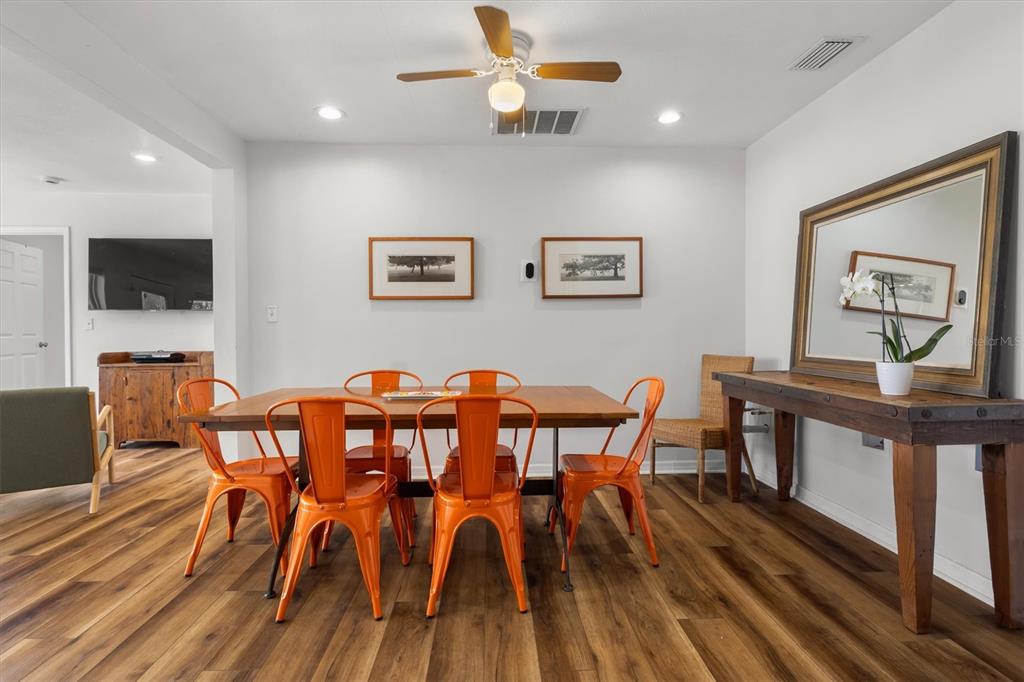 A dining room features a wooden table with orange metal chairs and wood-look flooring — 900 LAKE JESSIE DRIVE, WINTER HAVEN, FL