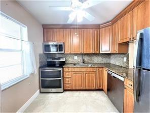 A kitchen with wood cabinets, granite countertops, stainless steel appliances, and a ceiling fan — 7300 NW 5th Court # 106, Margate FL 33063, MARGATE, FL