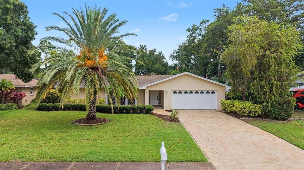 A single-story house with a beige exterior, a two-car garage, and a manicured hedge — 14317 110TH TERRACE, LARGO, FL