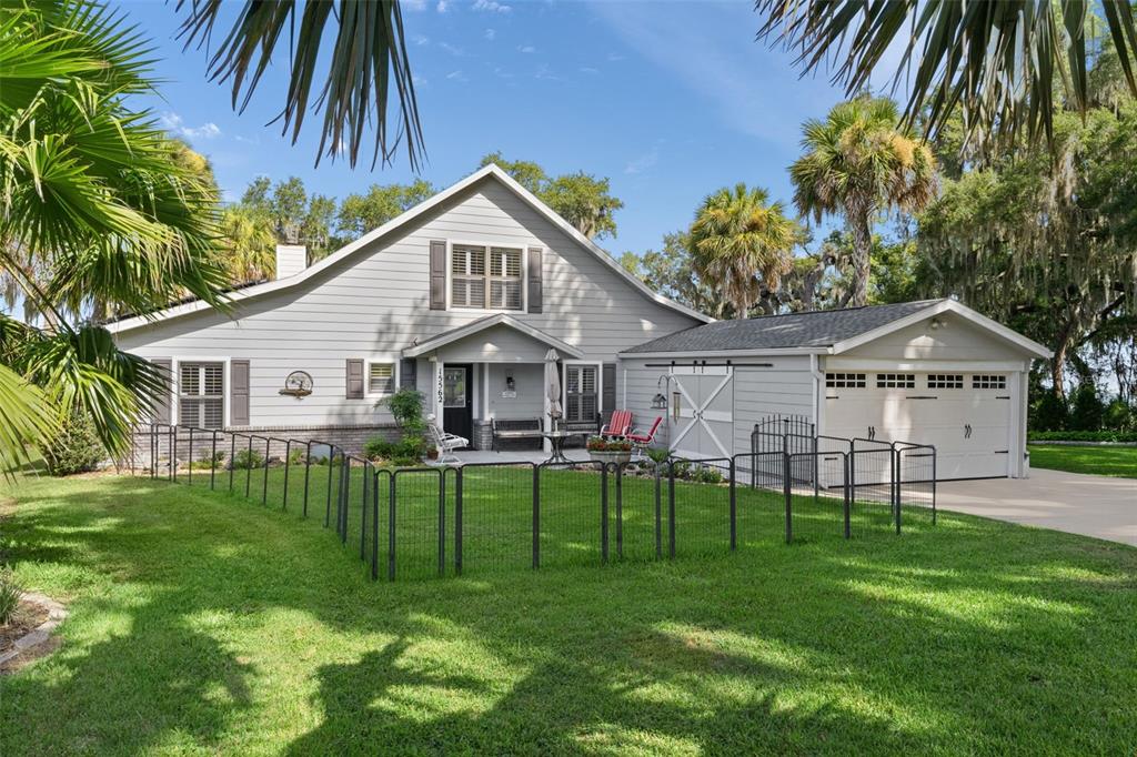 A gray house with a front porch, a garage, and a fenced-in lawn area — 15562 SE 138TH TERRACE, WEIRSDALE, FL