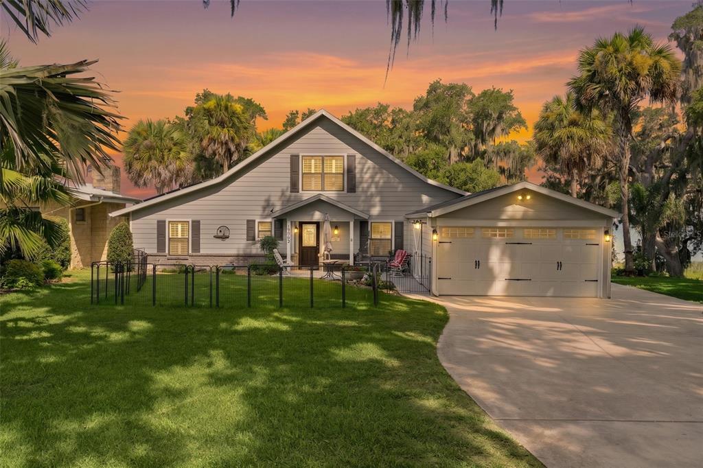 A two-story house with light gray siding, a two-car garage, and a fenced front yard — 15562 SE 138TH TERRACE, WEIRSDALE, FL