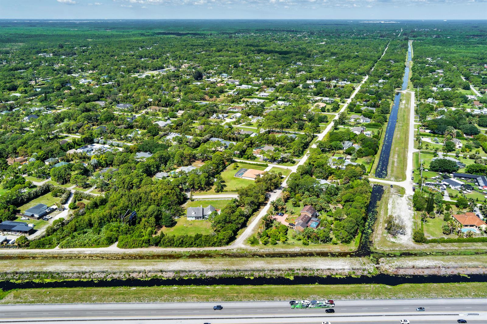 An aerial view shows a residential neighborhood bordering a canal and a multi-lane highway — 159th Court N, FL, FL