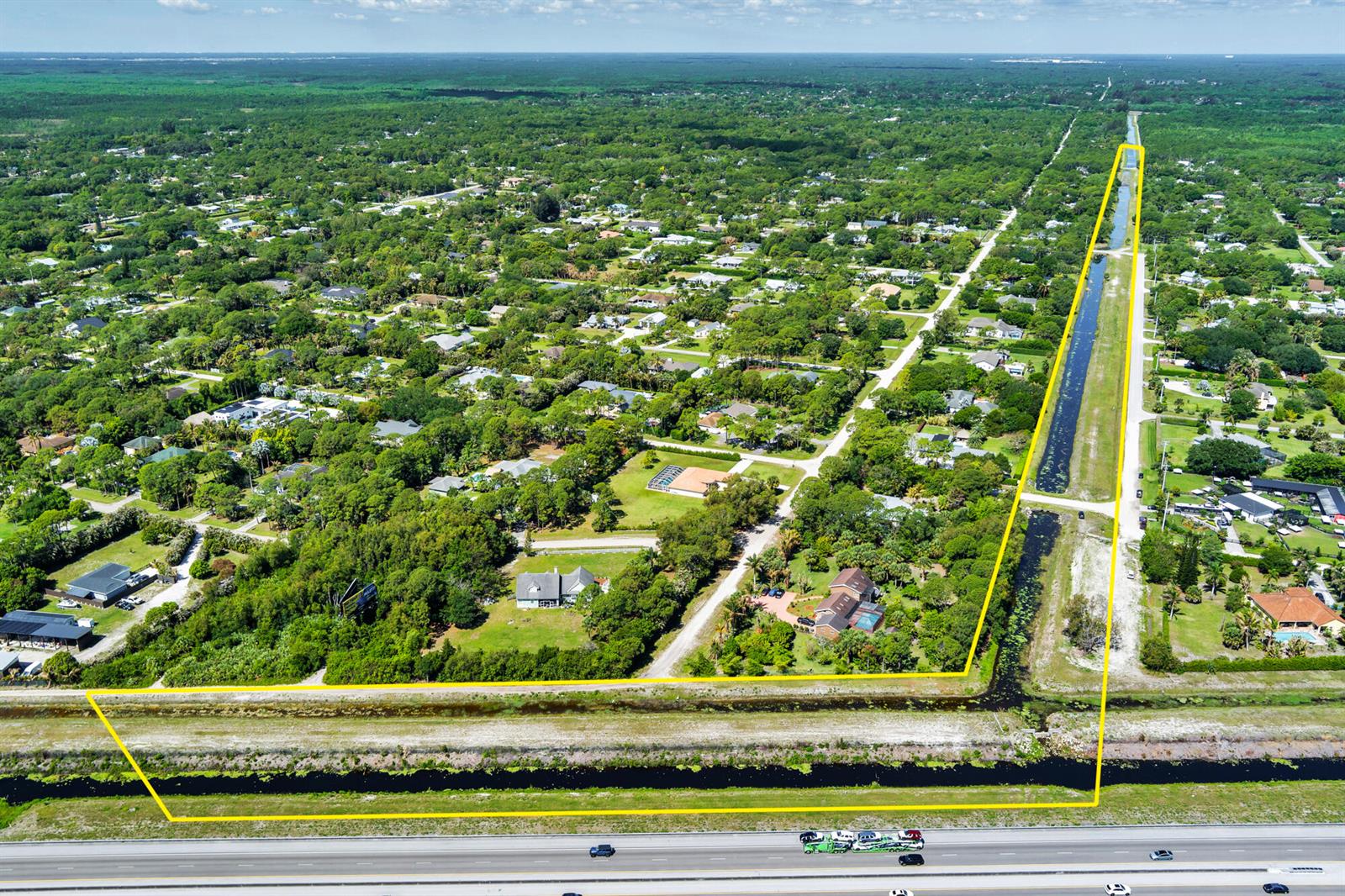 An aerial view shows a large, L-shaped parcel of land outlined in yellow near a highway — 159th Court N, FL, FL