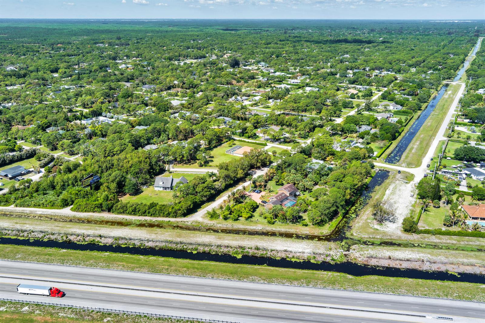 An aerial view shows a residential neighborhood bordering a highway and a drainage canal — 159th Court N, FL, FL