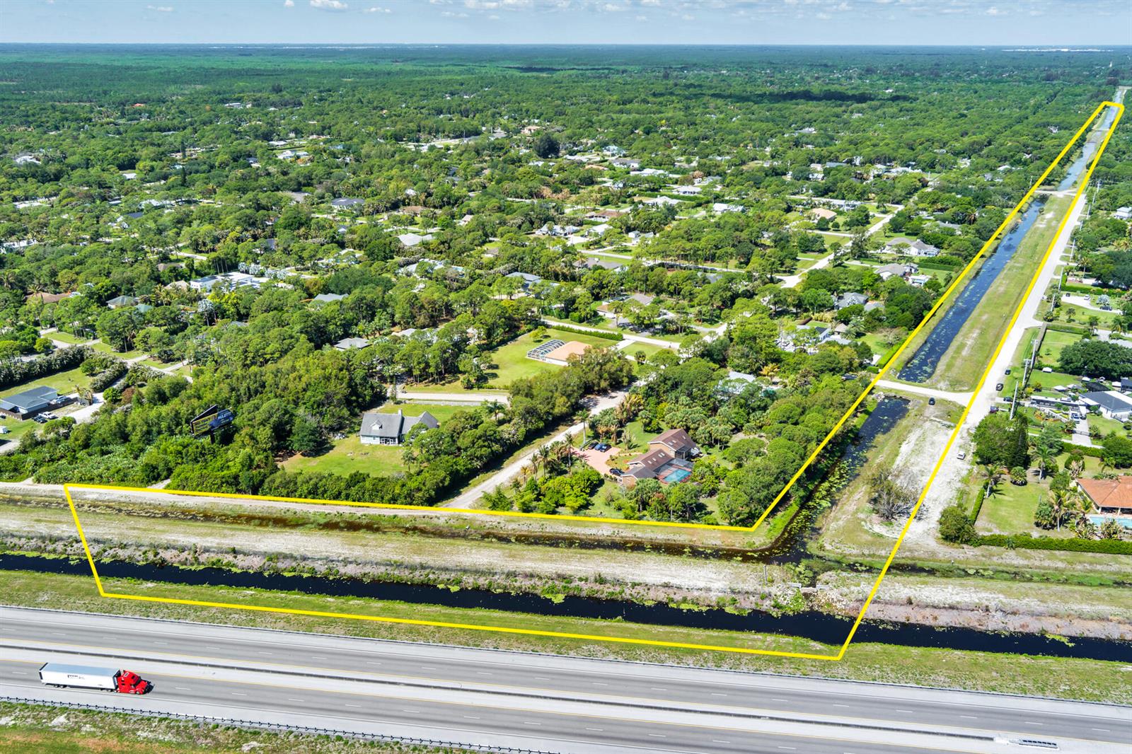 An aerial view shows a residential property bordered by a canal and a highway — 159th Court N, FL, FL