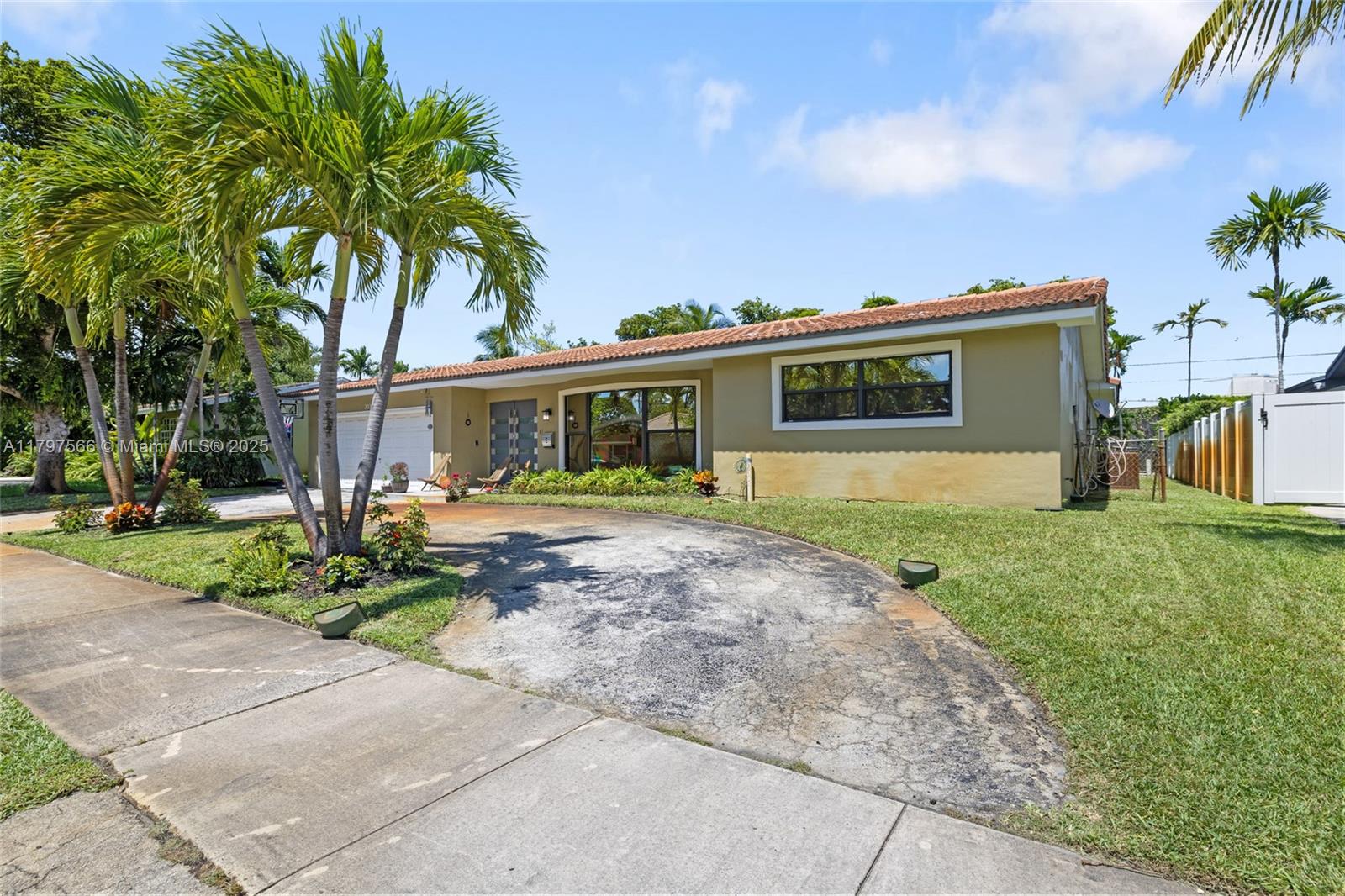 A single-story house with a tan exterior, a curved driveway, and palm trees in front — 20375 NE 22nd Pl, Miami FL 33180, MIAMI, FL