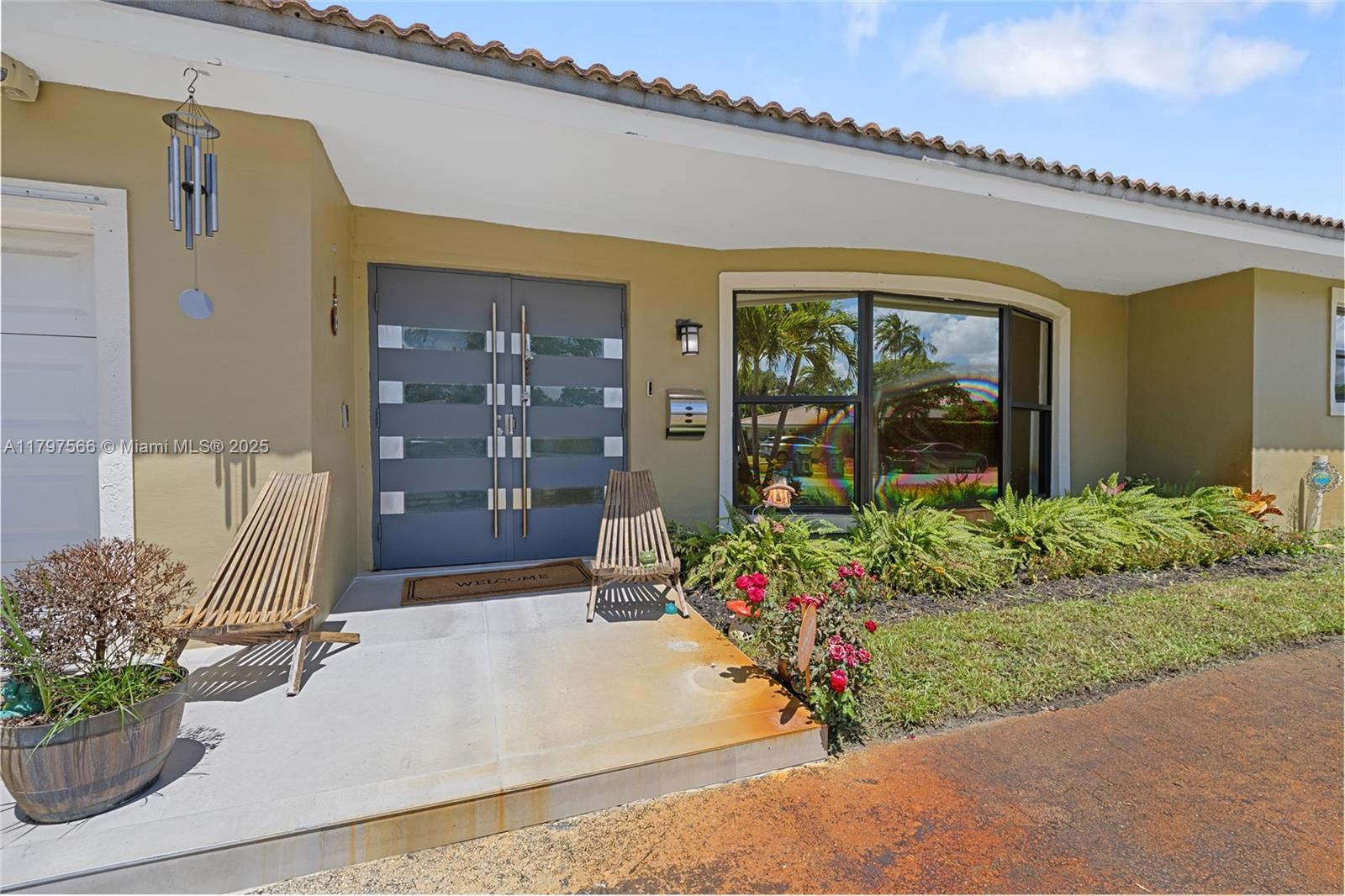 The exterior of a house features a gray double door, a large window, and chairs — 20375 NE 22nd Pl, Miami FL 33180, MIAMI, FL