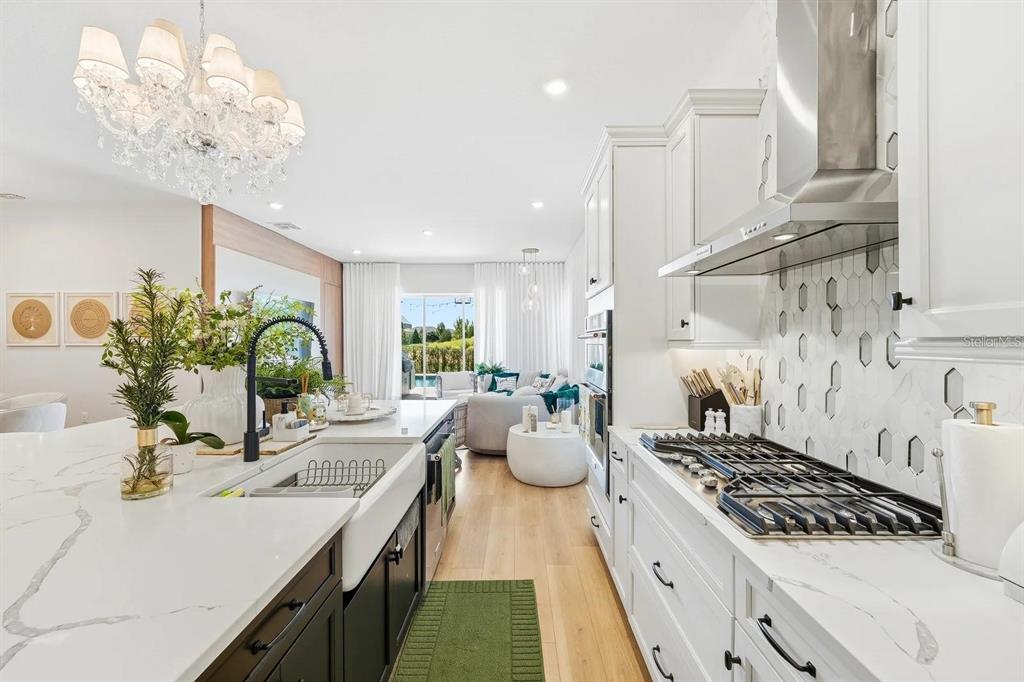 A modern kitchen features white cabinetry, a marble-topped island, and a farmhouse sink — 16312 VOLTERRA POINT, MONTVERDE, FL
