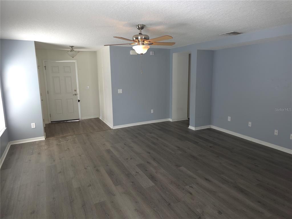 An empty room features gray walls, dark wood-look flooring, and a ceiling fan — 13812 CEPHEUS DRIVE, ORLANDO, FL