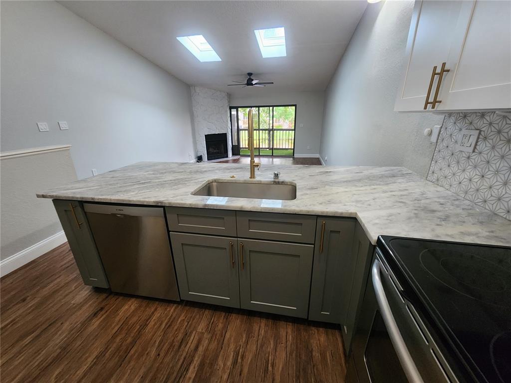 A kitchen island with a marble countertop and green cabinets faces a living area — 6236 93RD TERRACE N UNIT 3504, PINELLAS PARK, FL