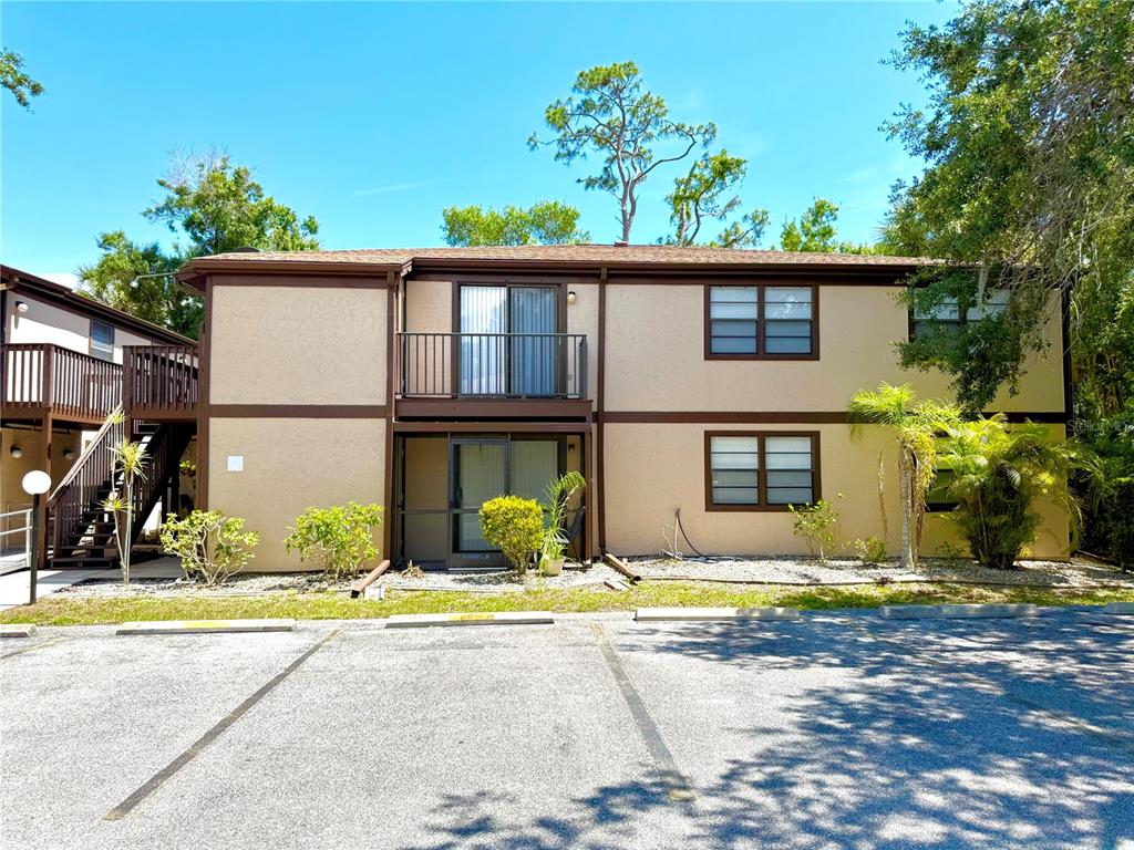 A two-story apartment building exterior features tan stucco walls, brown trim, and a parking lot — 4022 BEAVER LANE UNIT 1000H, PORT CHARLOTTE, FL