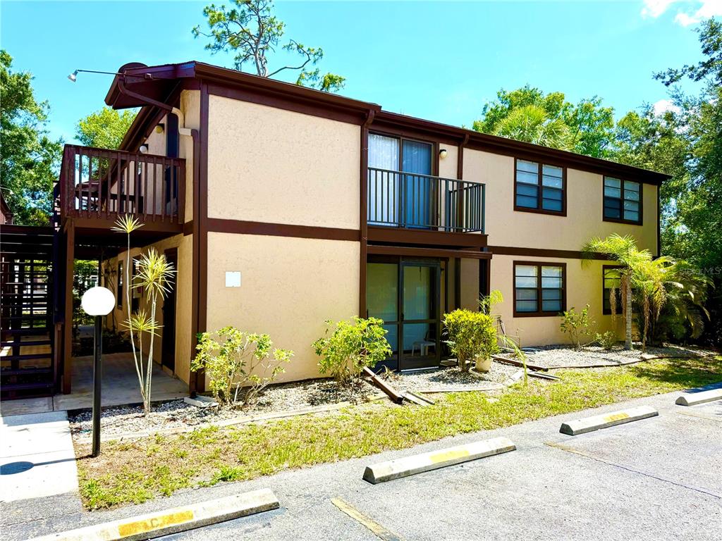 A two-story apartment building with tan stucco walls, brown trim, and exterior staircases — 4022 BEAVER LANE UNIT 1000H, PORT CHARLOTTE, FL